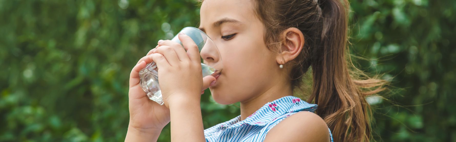 flicka är utomhus dricker rent vatten ur glas