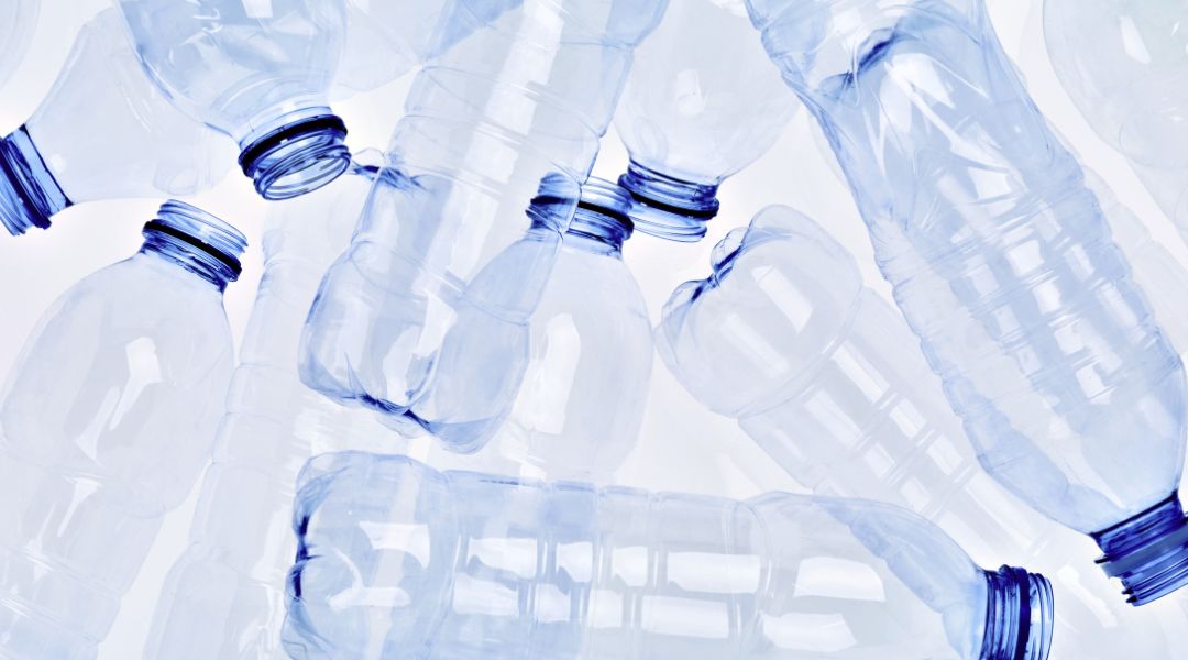 flera plastflaskor ligger huller om buller med en vit bakgrund