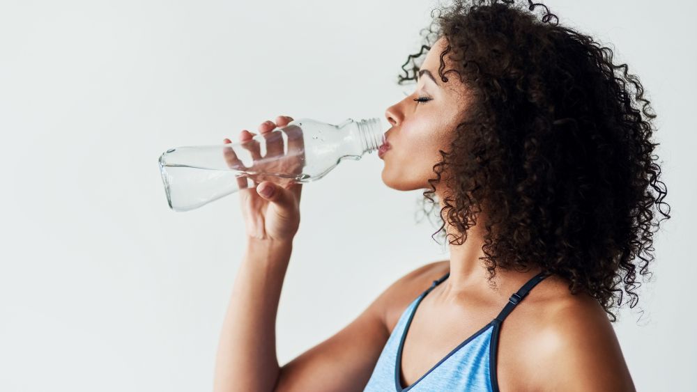 hälsosam kvinna dricker vatten ur flaska