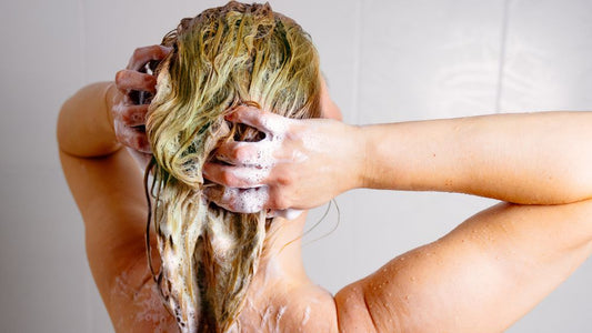 Kvinnas huvud i duschen shamponeras och har en grön nyans