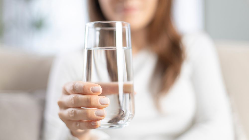 kvinna håller ett glas med rent dricksvatten
