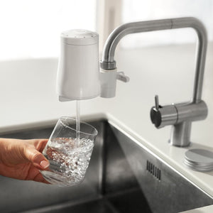 Tappwater ecofilter kranfilter rent vatten droppar ner i ett glas som en person håller i under kranen