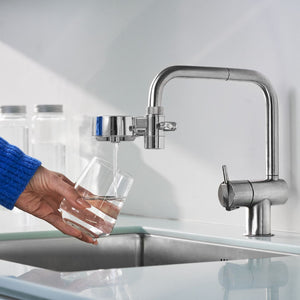 Ecofilter compact krom från tappwater, miljöbild på kran med kranfilter där rent vatten rinner ner i ett glas som en person håller i