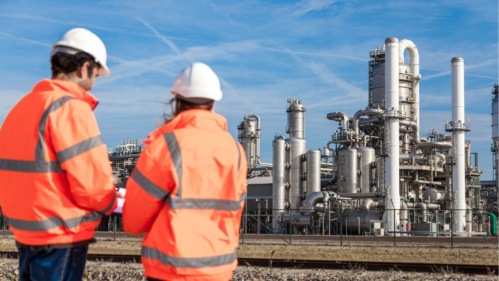 människor i orange jackor i industriområde