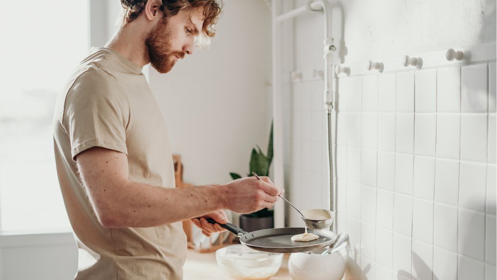 man steker pannkakor i kök